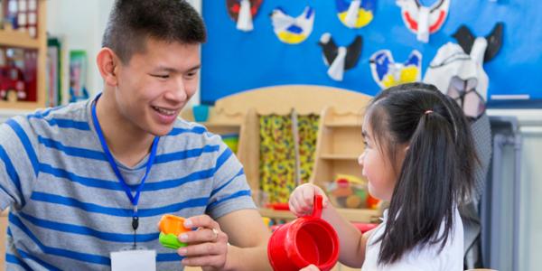 Teacher and young child playing at the water table in the classroom