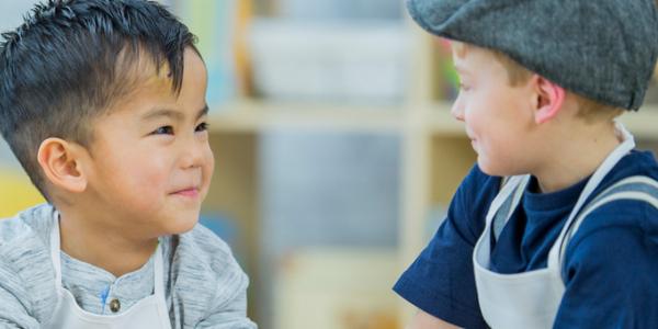 Two boys playing with and smiling at each other