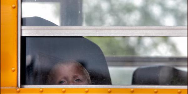 Little boy looking outside of school bus window