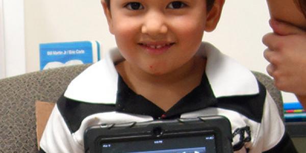 Child showing his artwork on a tablet.