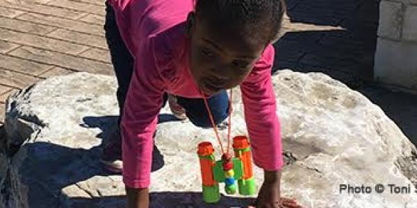 Young girl playing on rock outside