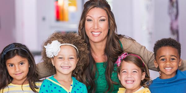 Teacher smiling with a group of young children.