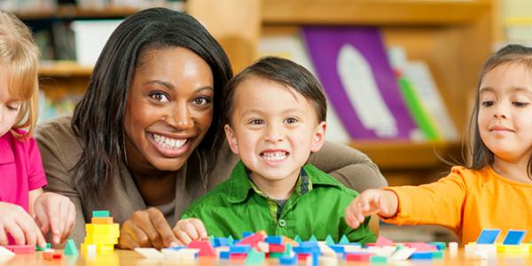 Teacher smiling with three preschoolers