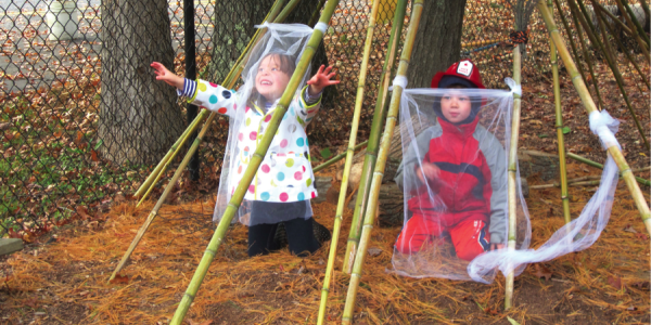 Two children playing outside under  long bamboo poles