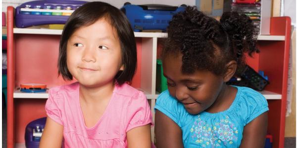 Two girls sitting close to each other, but not talking.