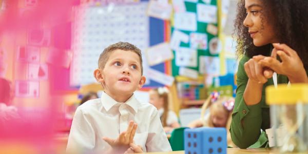 A young boy practices counting with his teacher.