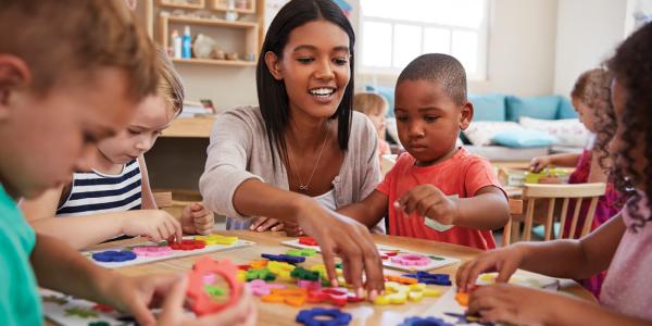 Teacher and diverse students at a table working with flower shapes