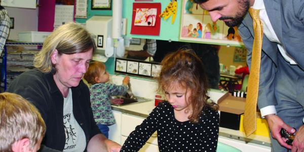 Two adults engage with children in a learning center