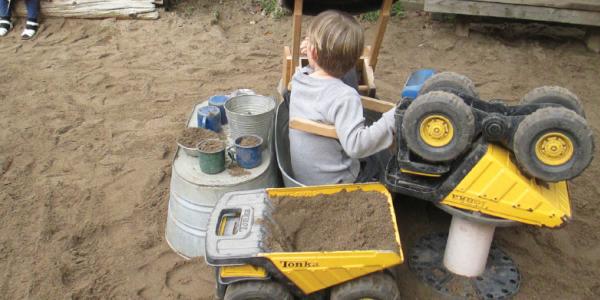 Child in poop machine in outdoor sandbox