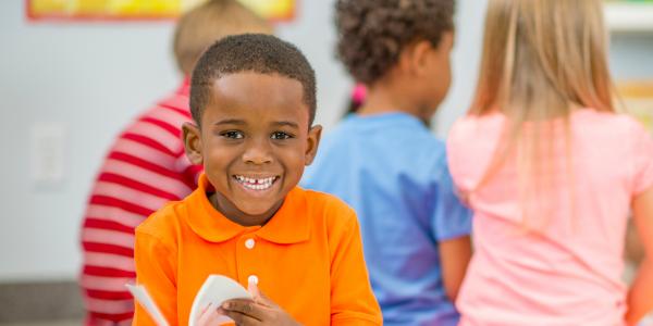 A young boy smiling and reading a book