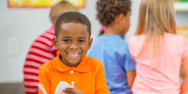 A young boy smiling and reading a book