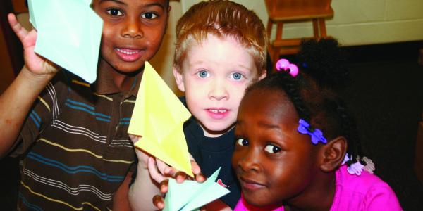 Three children hold up their paper animal creations.