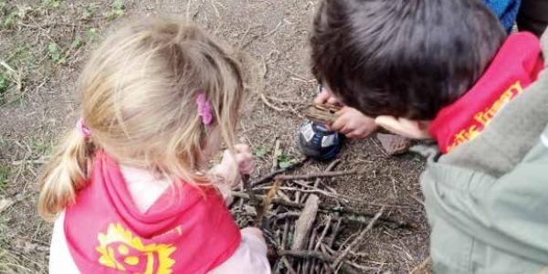 One child watches as another child pretends to build a fire.