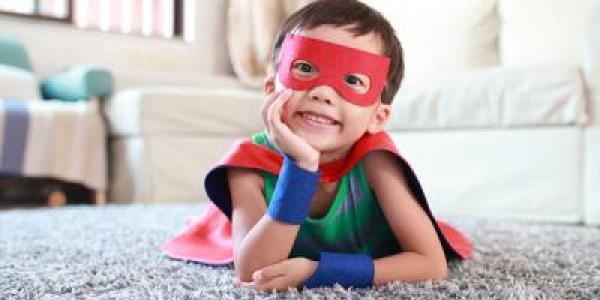 preschool boy dressed in a superhero cape and mask