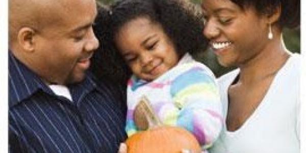 father, mother, and daughter holding a pumpkin
