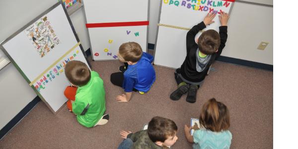 Five Kindergarten aged boys in a classroom playing with learning tools