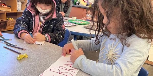 Children making signs in a classroom.