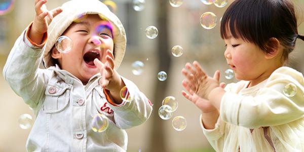 Two toddlers playing outside with bubbles