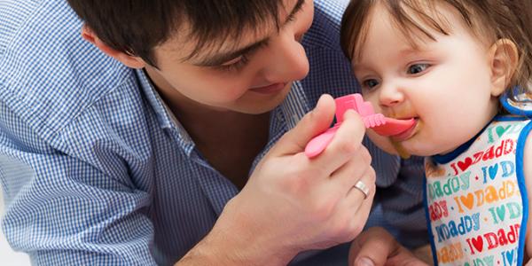 Father feeding his toddler daughter.