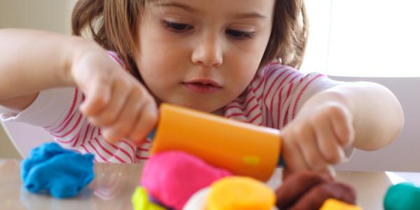 young girl rolling playdough