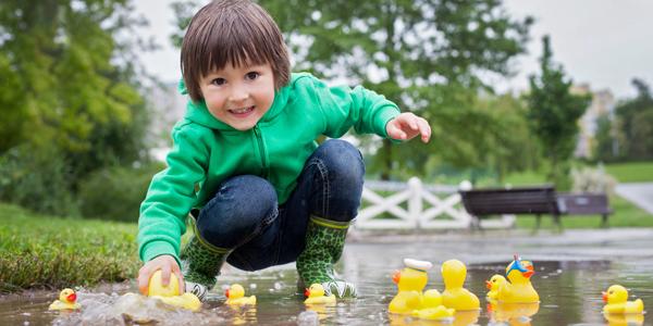 young boy plays with rubber ducks