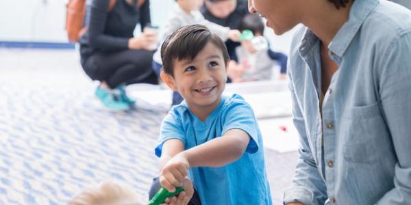 Child playing with recyclable materials with teacher