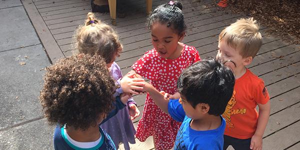 Five preschoolers standing outside holding hands