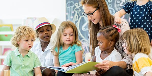 Teacher in a classroom reading to five children