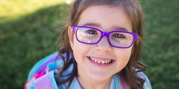 A young child with glasses smiling.