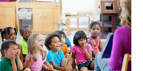 A teacher showing a picture book to children.