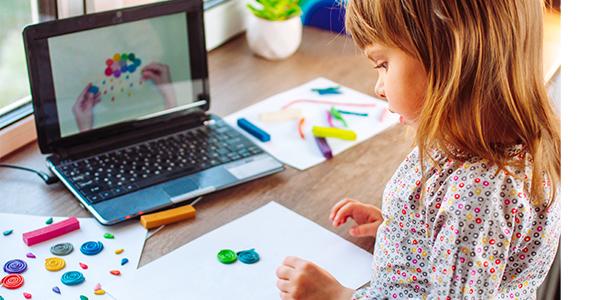  Una niña haciendo arte frente a una computadora.