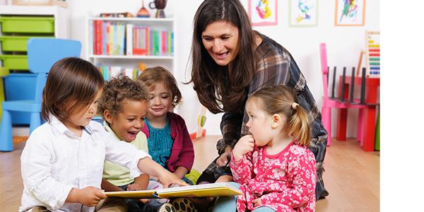 A teacher showing a picture book to children.