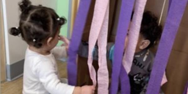 A toddler playing with streamers.