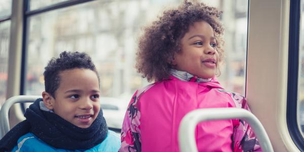 two kids sitting on a bus and looking out the window