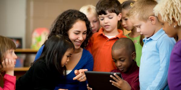 A group of children looking at an iPad with a teacher.