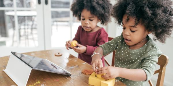 children playing with toys in front of an ipad