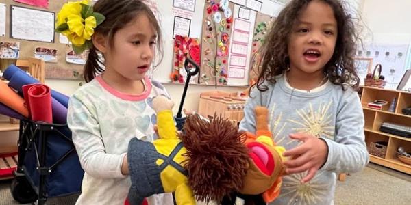 Two children playing with a puppet.