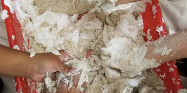 Children playing with sand and shaving cream at school