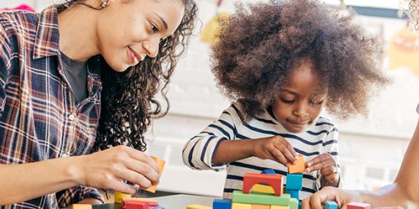 Two adults playing with blocks with a preschooler 