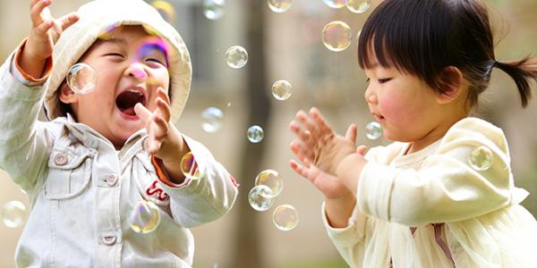 Two toddlers playing outside with bubbles