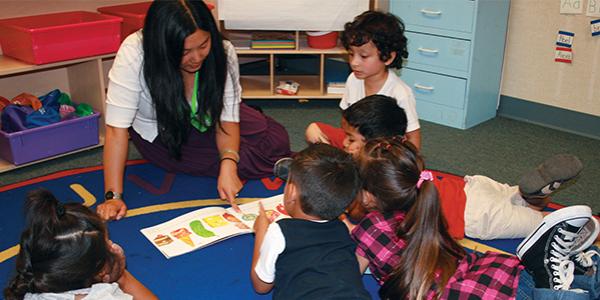 Preschool teacher showing students a picture book