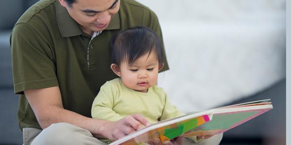 Father and daughter ready a book together on the floor