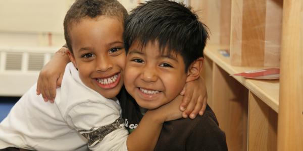 Two young boys hugging in a classroom