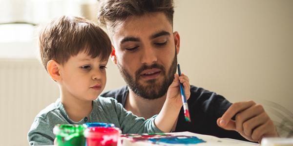 Young adult male painting with a preschool boy