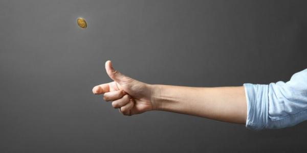 Person's hand flipping a coin