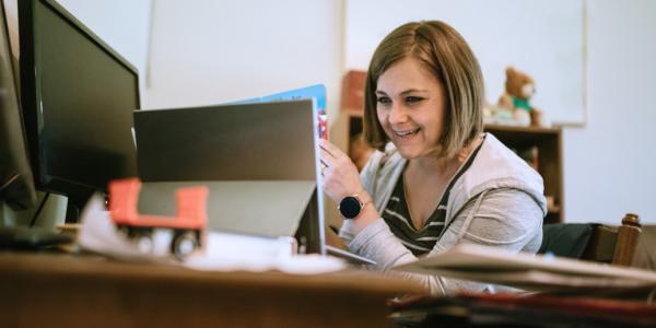 A teacher smiling at a computer