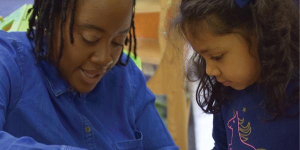 A teacher showing a craft to a child.