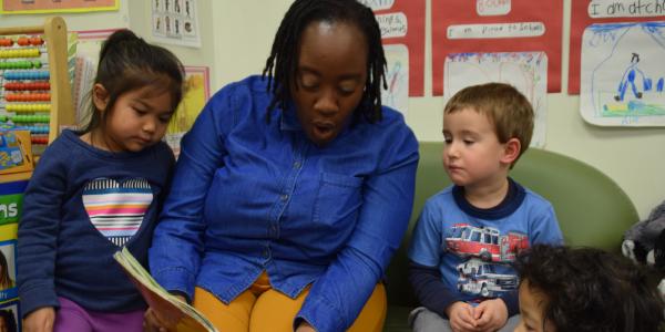 A teacher reading to two children.