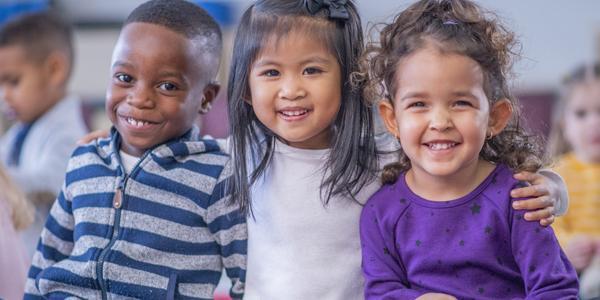 three children sitting and smiling 