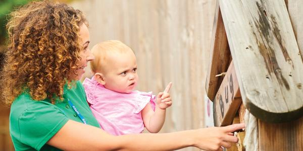 A person holding a toddler and showing them the world